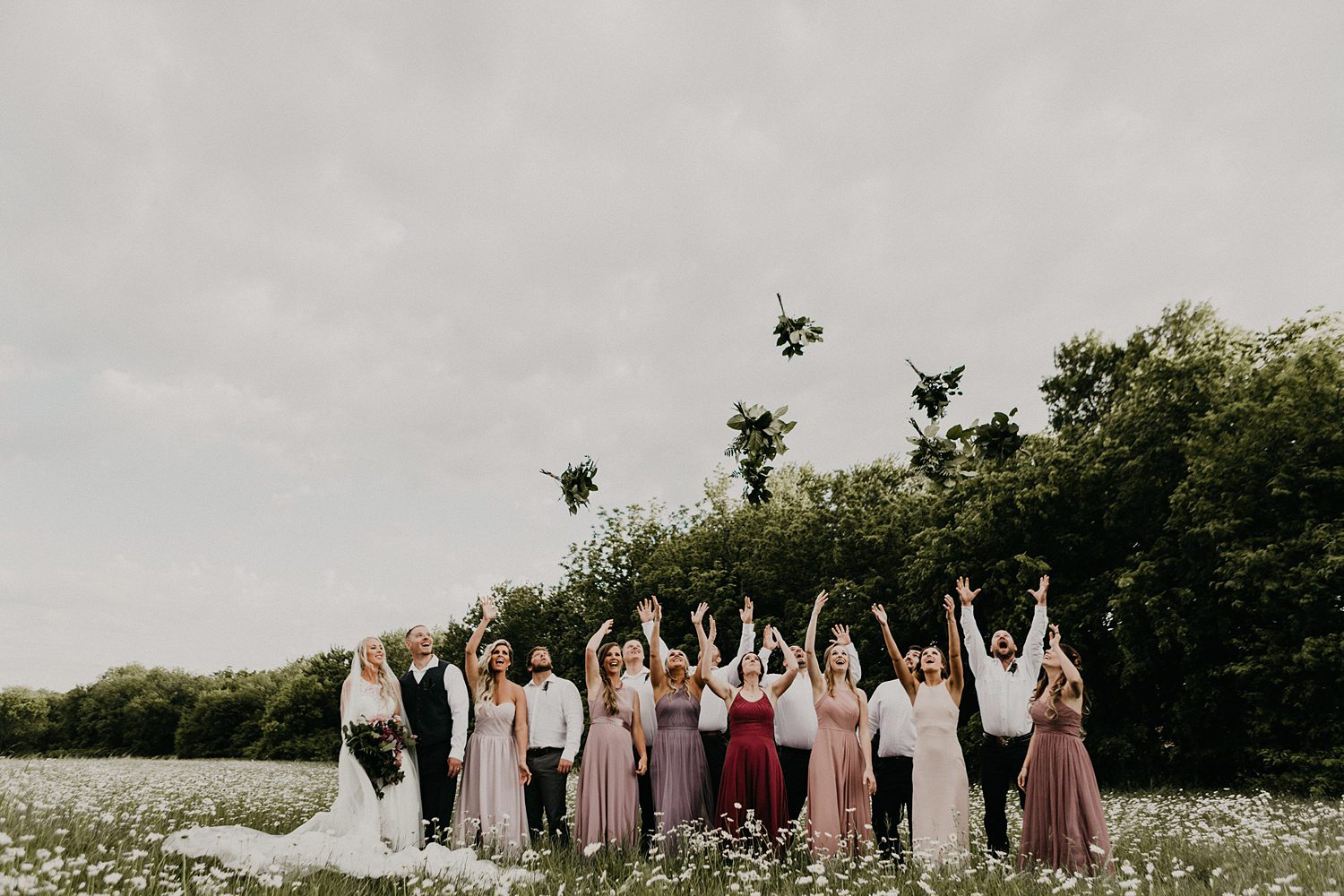 brides throwing Boquete in the air muted tone dresses